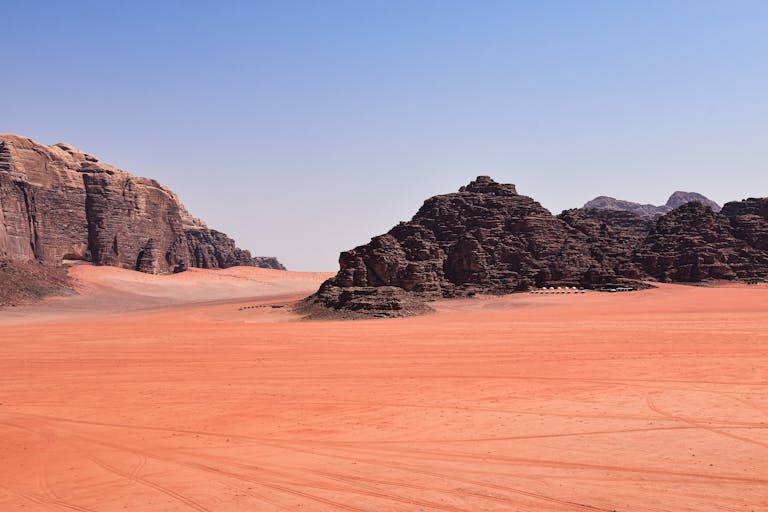 Explore the stunning rock formations and sandy landscapes of Wadi Rum in Jordan, under a clear blue sky.