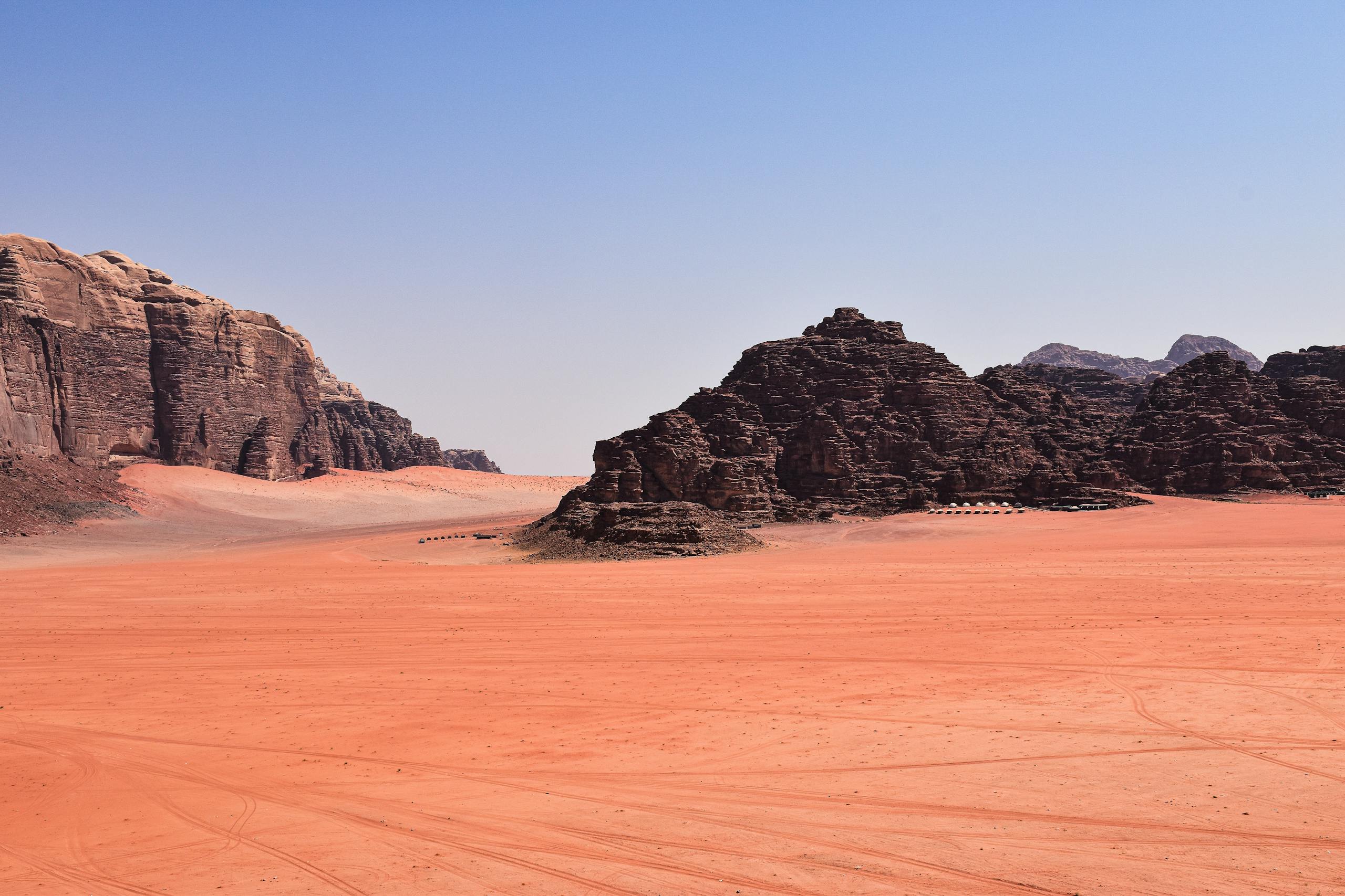 Explore the stunning rock formations and sandy landscapes of Wadi Rum in Jordan, under a clear blue sky.